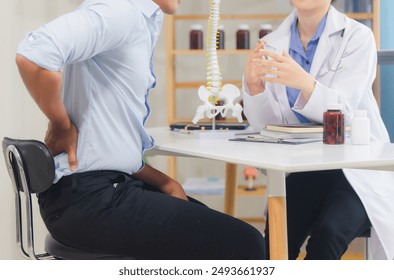 An orthopedic doctor shows a spinal model to a patient in a human spinal hospital. Diseases and disorders of the spinal cord, back pain, lumbar pain, orthopedic surgery, chiropractic, office syndrome
