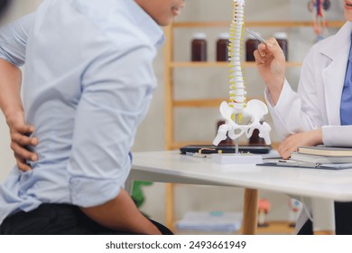 An orthopedic doctor shows a spinal model to a patient in a human spinal hospital. Diseases and disorders of the spinal cord, back pain, lumbar pain, orthopedic surgery, chiropractic, office syndrome - Powered by Shutterstock - Get 15% off with code: PIKWIZARD15