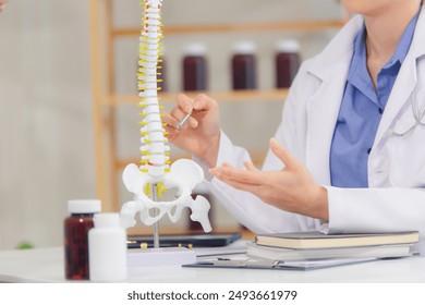 An orthopedic doctor shows a spinal model to a patient in a human spinal hospital. Diseases and disorders of the spinal cord, back pain, lumbar pain, orthopedic surgery, chiropractic, office syndrome - Powered by Shutterstock