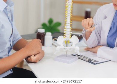 An orthopedic doctor shows a spinal model to a patient in a human spinal hospital. Diseases and disorders of the spinal cord, back pain, lumbar pain, orthopedic surgery, chiropractic, office syndrome