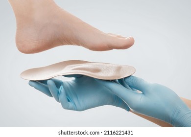 Orthopedic Insole Isolated On A White Background. Hands In Rubber Gloves Hold An Orthopedic Insole. Foot Care, Comfort For The Feet. Doctor Orthopedist Tests The Medical Device. Flat Feet Correction.
