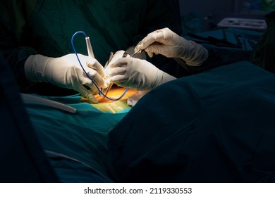 Orthopedic surgeons hands in sterile gloves with specific instruments and a suction tube operating the human spine for minimal invasive spinal surgery
