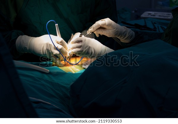 Orthopedic surgeons hands in sterile gloves with\
specific instruments and a suction tube operating the human spine\
for minimal invasive spinal\
surgery