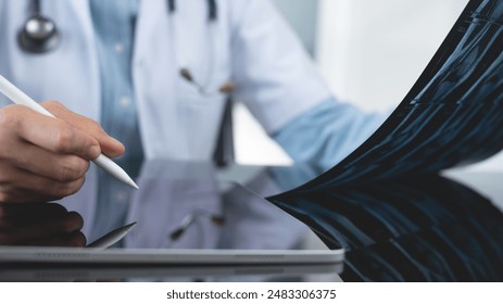 Orthopedics surgeon doctor using digital tablet and examining and recording patient's knee joint x-ray films, MRI bone, ct scan at radiology orthopedic unit in hospital. knee joint film x ray - Powered by Shutterstock