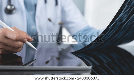 Orthopedics surgeon doctor using digital tablet and examining and recording patient's knee joint x-ray films, MRI bone, ct scan at radiology orthopedic unit in hospital. knee joint film x ray