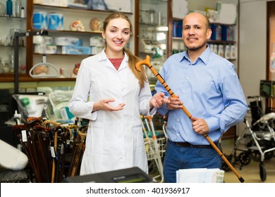 Orthopedist consulting elderly client about walking sticks in shop - Shutterstock ID 401936917