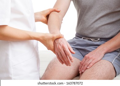 Orthopedist examining injured  arm of man in middle age - Powered by Shutterstock