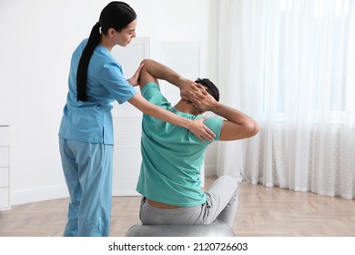 Orthopedist helping patient to do exercise in clinic. Scoliosis treatment - Powered by Shutterstock