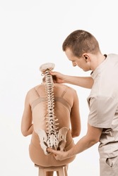 Orthopedist Showing Spinal Column Model With Girl On White Background. Scoliosis Is Sideways Curvature Of The Spine. Backbone Anatomical Model With Young Woman