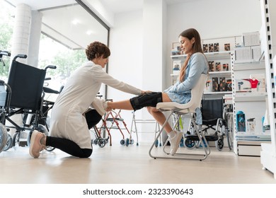 Orthopedist woman putting a knee brace on a young client - Powered by Shutterstock