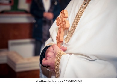 Ortodox priest holding a cross while christening 