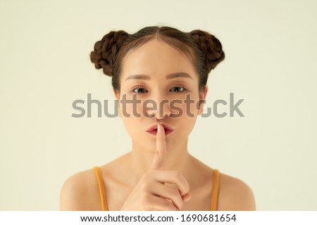 ortrait of funny young pretty girl with two buns making funny face fooling over white background.