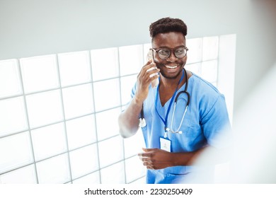 ortrait Of Male Nurse Wearing Scrubs In Exam Room. A male nurse is standing in the doctor's office wearing scrubs and a stethoscope. He is smiling and looking at the camera. - Powered by Shutterstock