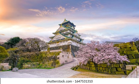 Osaka Castle With Full Bloom Of Sakura In Japan At Sunset