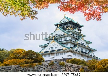 Osaka Castle in Osaka,Kansai,Japan in Fall or Autumn season. Maple tree are turn into red and orange leaf. There are red leaf in foreground.It is one of most famous landmark in Japan