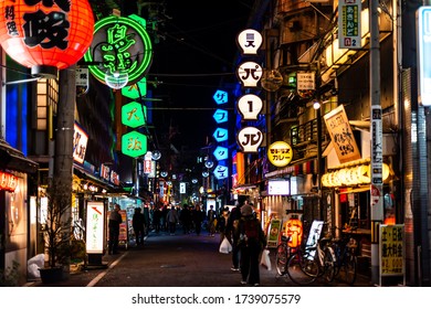 Osaka, Japan - April 13, 2019: Minami Namba Famous Street With People Walking In Dark Night And Illuminated Red Green Neon Buildings With Red Paper Lanterns