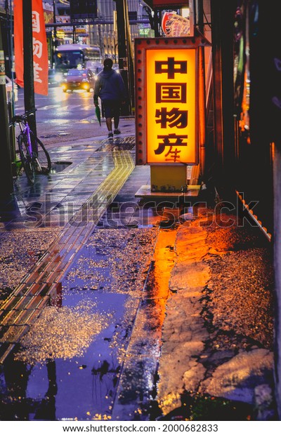 Osaka, Japan -\
Circa 2015: Traditional restaurants people walking, traffic,\
lights, neons and signs in a rainy night with reflections in the\
floor at Nipponbashi in the\
night