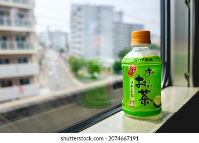 Osaka, Japan: ITO EN Oi Ocha Ryokucha Green Tea Bottle At Train Window With Cityscape Outside