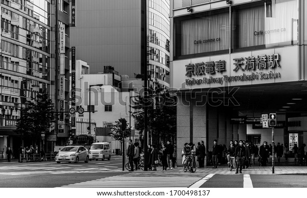 Osaka, Japan - January, 2020: A black and white\
picture of an intersection in Osaka, next to the Keihan Railway\
Temmabashi Station.