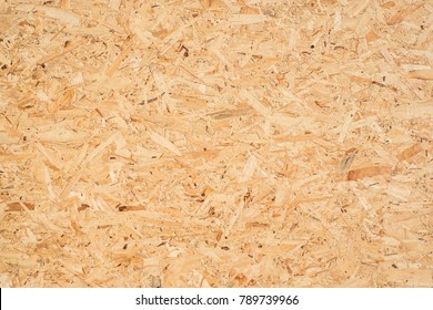 OSB boards are made of brown wood chips sanded into a wooden background. Top view of OSB wood veneer background, tight, seamless surfaces. - Shutterstock ID 789739966