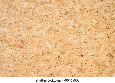 OSB boards are made of brown wood chips sanded into a wooden background. Top view of OSB wood veneer background, tight, seamless surfaces. - Shutterstock ID 790465003