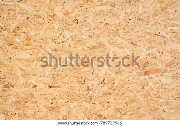 OSB boards are made of brown wood chips sanded\
into a wooden background. Top view of OSB wood veneer background,\
tight, seamless surfaces.