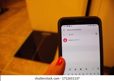 Oshkosh, WI / USA - April 12, 2020: A Mentally Troubled Woman Texts 741741 To Contact The National Suicide Prevention Lifeline While Sitting In Front Of Her Scale.