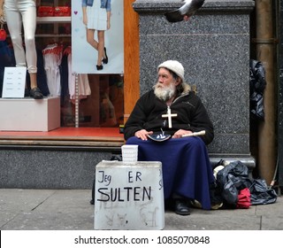 Oslo, Norway -05-10-2014: Old Man Sitting In The Street Begging For Money. Bird Is Flying Over Him.  Written Text Says 'I'm Hungry'