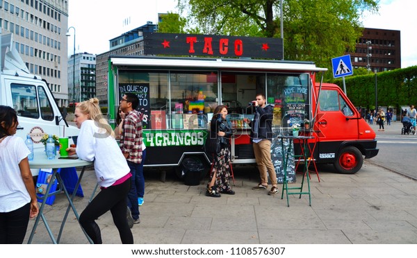Oslo, Norway -05-13-2018: Food truck, mobile\
kitchen in the Oslo Harbor. Tacos for gringos. Home made Mexican\
food. Young people enjoying the Mexican food in Oslo Harbor. Queso\
and quesadillas, yummy!