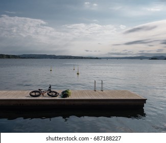 Oslo, Norway - 20 May 2017 - Man Lying Down Beside His Fat Bike On Wood Jetty In The Oslo Fjord On Sunny Summer Day