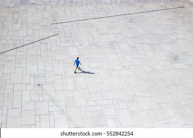 OSLO, NORWAY - AUG 10, 2016. Downright View At A Lonely Man Walking Like Ant On White Pavement Near Oslo Opera House. View From The Roof Of Opera In Sunny Summer Day. Isolated Man On White Background