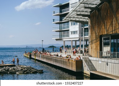 OSLO, NORWAY - JULY 28, 2019: People Sunbathing On A Hot Sunny Summer Day In City Center, Tjuvholmen Neighborhood