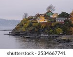 Oslo, Norway - October 20, 2024: Oslofjord (Oslofjorden), view of summer houses and cottages. Frame houses for recreation. Hut among the forest and rocks. Multicolored private houses.