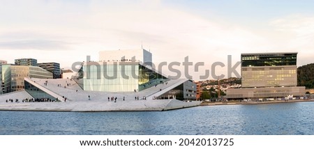 Oslo, Norway. Scenic Night Evening View Of Illuminated Norwegian National Opera And Ballet House Among Contemporary High-Rise Buildings. Panorama, Panoramic View.