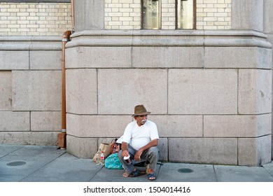 Oslo, Norway - Sep 13, 2019: Old Man Pauper Tramp Sitting On The Street Begging Alms. Social Concept Of Poverty Line.   