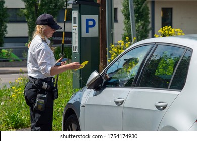 Oslo.Oslo / Norway - 06 11 2020: Young female parking officer is writing a fine ticket. In a picture you can see a car, parking ticket machine and officer.