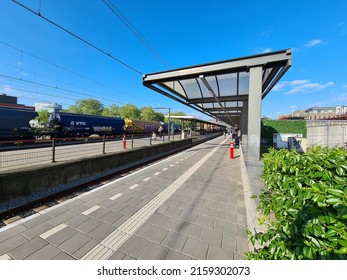 Oss, North Brabant, The Netherlands - May 11 2022. Oss Central Station Early In The Morning. Left A Freight Train And In The Middle People Waiting For The Next Passenger Train.