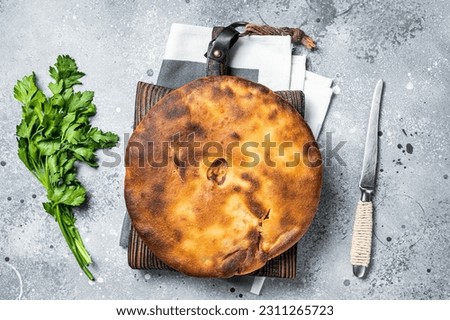 Ossetian pie with beef meat and herbs on wooden board. Gray background. Top view. Stock photo © 