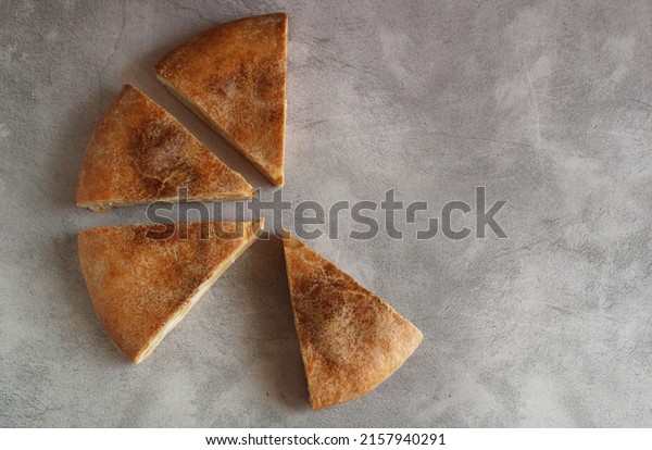 Ossetian round cake with filling cut into\
pieces on a gray\
background