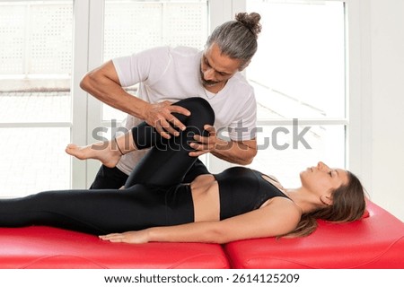 Osteopath checking hip joint mobility of female patient during a physical therapy session