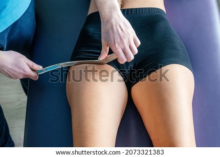 Osteopath is demonstrating Active release techniques ART or Soft tissue Release STR for the rectus femoris tendon with IASTM tool