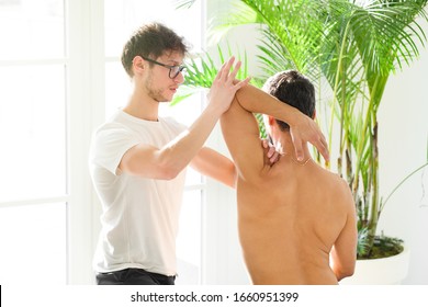 Osteopath doing a shoulder evaluation on a man flexing and rotating the joint to assess mobility