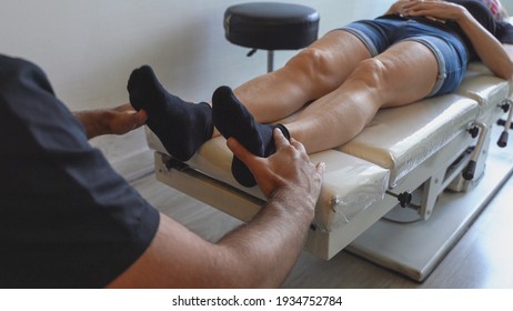 Osteopath Holding Feet Of Female Patient Lying On Stretcher. Chiropractic Manipulation, Doctor Office, Medical Examination Concepts