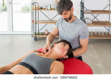 Osteopath performing a Sternocleidomastoid myofascial massage on a young woman patient manipulating the neck muscles with his fingers to relieve pain