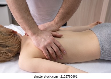 The Osteopath Works With The Spine. A Teenage Child Lies On A Couch In Front Of A Doctor. A Chiropractor Examines The Spine. Posture Correction