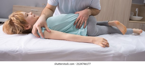 An Osteopathic Doctor Is Working With The Child. Work On Twisting The Spine. Teenage Girl Patient Chiropractor. Posture Correction