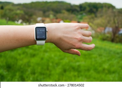 OSTFILDERN, GERMANY - APRIL 26, 2015: A Middle Aged Caucasian Woman Is Checking Her Apple Watch Displaying The Home Screen With A Reminder Of A Current Meeting In Her Calendar While Walking In The