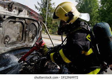 Ostrava, Czech Republic - July 30 2019: A Firefighter With A Breathing Apparatus Extinguishes A Car Engine Fire With Water