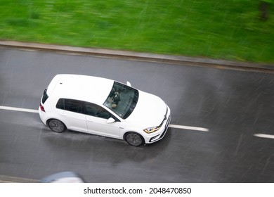 OSTRAVA, CZECH REPUBLIC - MAY 13, 2021: White Volkswagen Golf car in a strong thunderstorm with a heavy rain. Dangerous driving conditions and aquaplanning risk