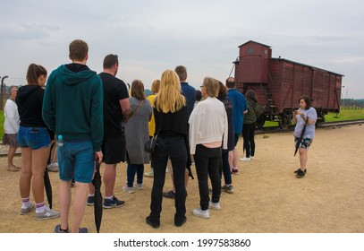 Oswiecim, Poland - July 11th 2018.  A tour group crowds around their guide as she explains about the Train Wagon on the unloading platform at the Birkenau-Auschwitz II concentration camp. 